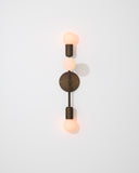 Modern wall sconce with three visible light bulbs on a light gray background