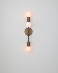 Wall-mounted light fixture with three visible bulbs on a plain background