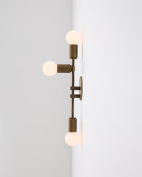 Modern wall-mounted light fixture with three exposed bulbs on a white background