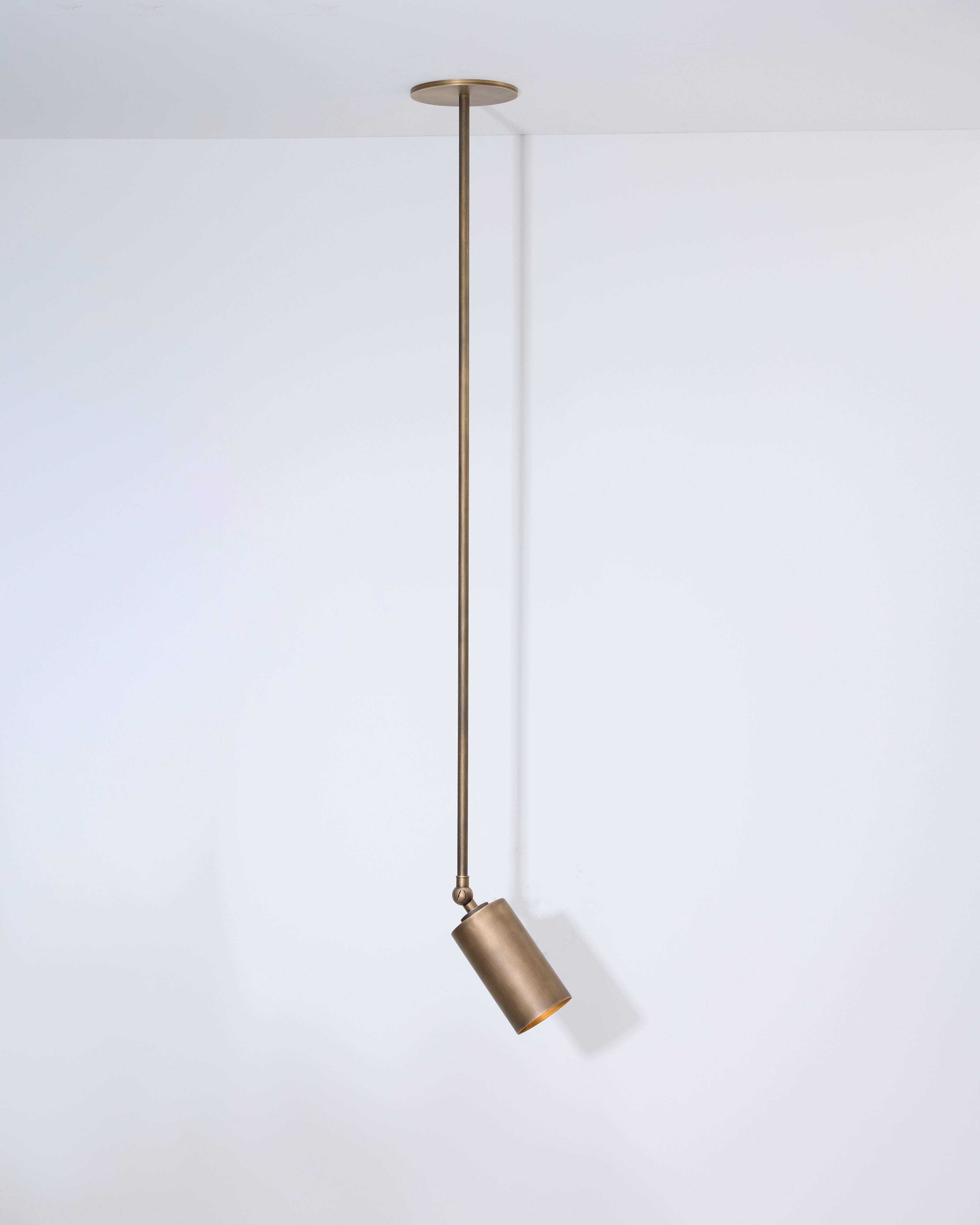 Brass pendant light hanging against a white background