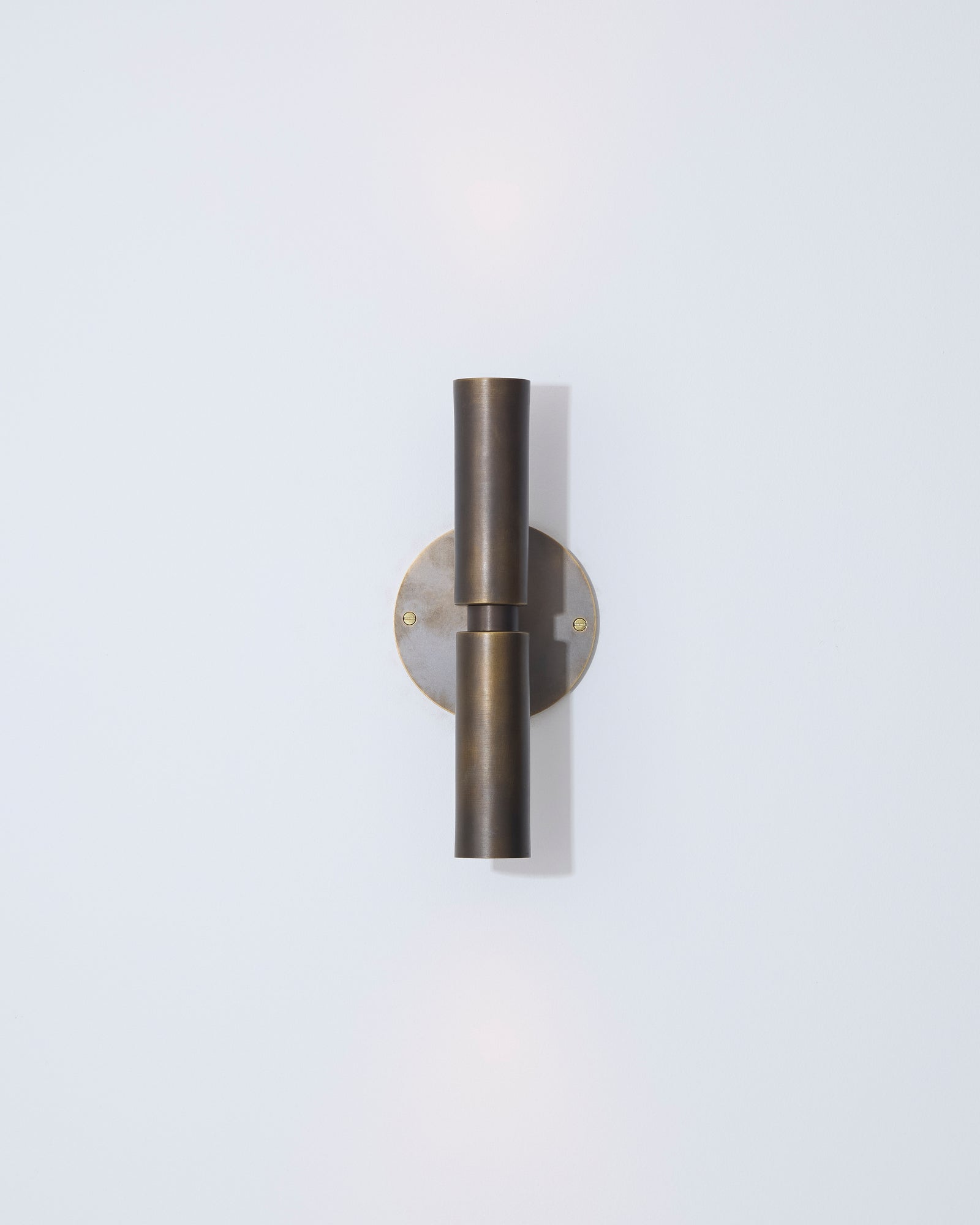 Wall-mounted light fixture with a metallic finish on a light gray background