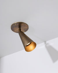 Brass ceiling light fixture on a white wall with a gray ceiling