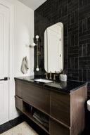 Bathroom with dark tiled wall, wooden vanity, and mirror.