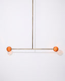 Modern pendant light with orange spherical shades on a white background