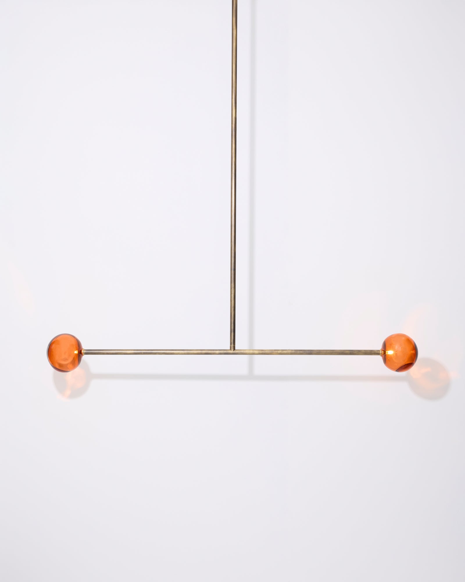 Modern pendant light with orange spherical shades on a white background