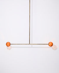 Modern pendant light with orange spherical shades on a white background