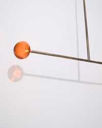 Modern pendant light with orange glass shade on a white background