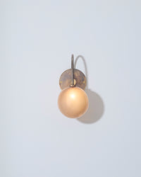 Wall-mounted light fixture with a round bulb on a light gray background