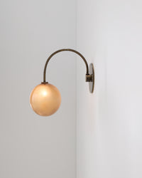 Wall-mounted lamp with a gold bulb on a white wall